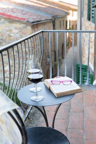a table with a glass of wine and a book at Palazzo Malaspina B&B in Tavarnelle in Val di Pesa