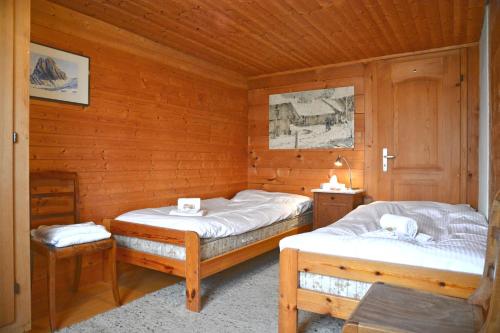 AeschiにあるTraditionelles Chalet Schärmtanneの木造キャビン内のベッド2台が備わる部屋