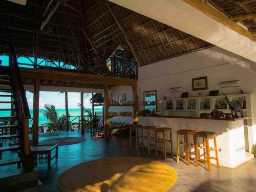 a room with chairs and a bar with the ocean at Hekaya Zanzibar in Pingwe