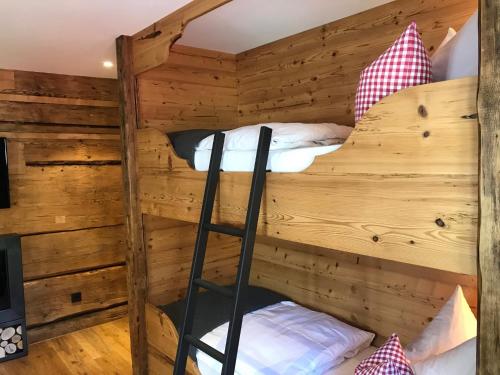 two bunk beds in a wooden room with a ladder at Gästehaus Fritz in Mittelberg