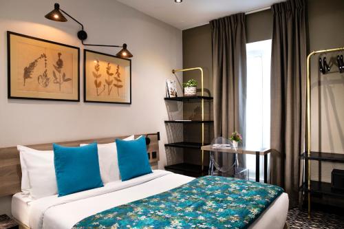 a bedroom with a bed with blue pillows at H&ocirc;tel Maxim Quartier Latin in Paris