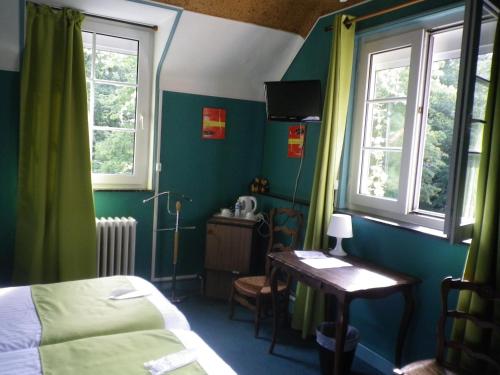 ein Schlafzimmer mit einem Bett und einem Schreibtisch und zwei Fenstern in der Unterkunft Hotel Ermitage du Moulin Labotte in Haybes