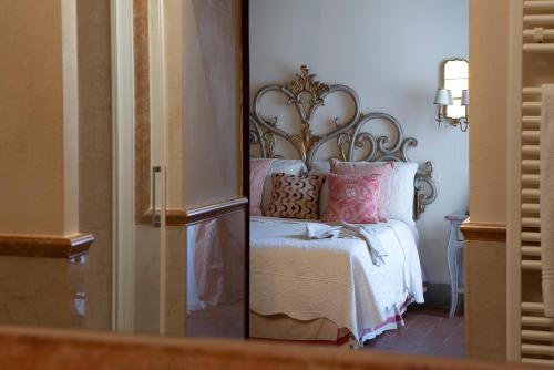 a bedroom with a bed with pink pillows and a mirror at Palazzo Malaspina B&B in Tavarnelle in Val di Pesa