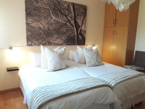 Un dormitorio con una cama blanca con un cuadro en la pared. en Thokazi Royal Lodge, en Nongoma