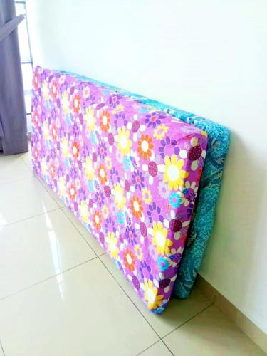 a purple pillow with flowers on it sitting on the floor at Desaru Cosy Homestay - near WaterPark, Beach, Rapid -Wifi, TVbox, Steamboat, BBQ Available in Desaru