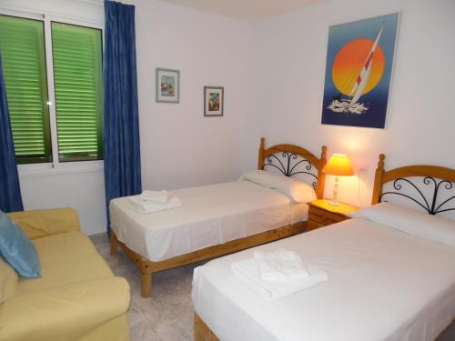 Cette chambre comprend deux lits, une chaise et un canapé. dans l'établissement Apartamento Playa Mar Azul, à Alcúdia
