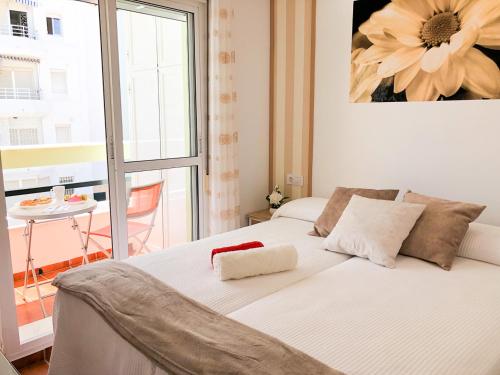 Schlafzimmer mit einem weißen Bett und einem großen Fenster in der Unterkunft Summerland Apartments Rota in Rota