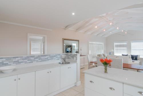 a kitchen with white cabinets and a dining room at Pezula Afternoon Delight NT3 in Knysna