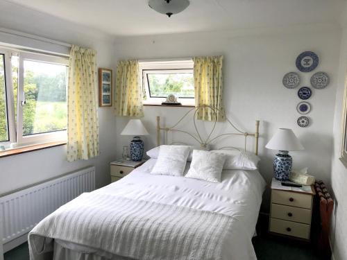 a bedroom with a white bed and two windows at Holly House B&B in Sittingbourne