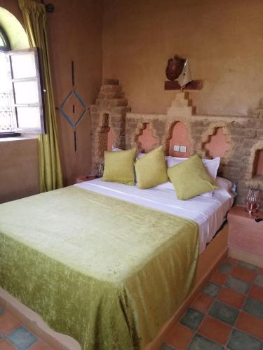 a bedroom with a large bed with yellow pillows at Riad Dar Poublanc in Merzouga