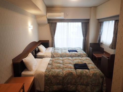 a hotel room with two beds and a window at Castle Inn Komaki in Komaki