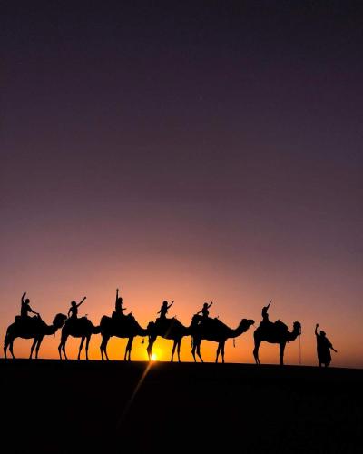 a group of people riding on the horses at sunset at Riad Dar Poublanc in Merzouga