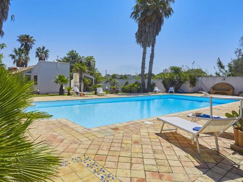 a swimming pool with a chair and palm trees at Lush Villa with Private Swimming Pool in Marsala Sicily in Marsala