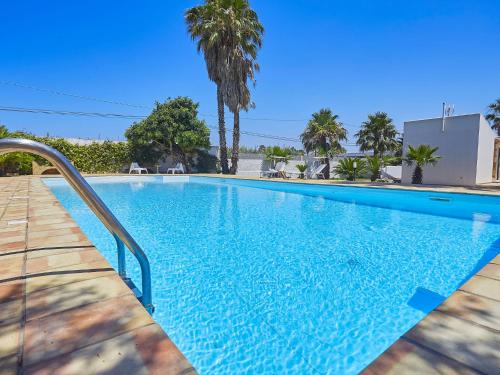 a swimming pool with blue water and palm trees at Lush Villa with Private Swimming Pool in Marsala Sicily in Marsala