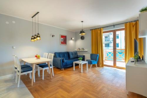 a living room with a table and a blue couch at RentPlanet - Apartamenty Szrenica in Szklarska Poręba