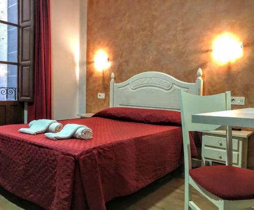 a hotel room with a bed, chair, table and lamp at Hostal Sonia in Granada