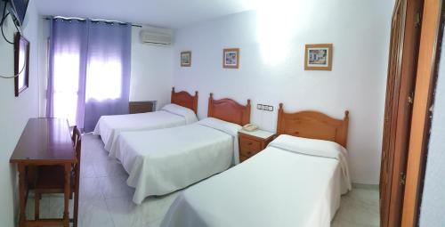 コルドバにあるHotel La Lanchaのベッド3台、テーブル、デスクが備わる客室です。