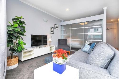 a living room with a couch and a tv at Deluxe Princes Wharf Apt l FREE WIFI & AIRCON in Auckland
