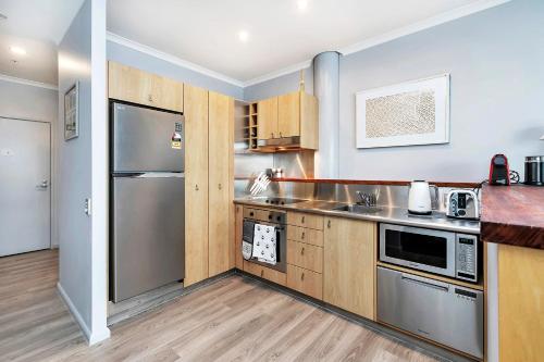 a kitchen with stainless steel appliances and wooden cabinets at Deluxe Princes Wharf Apt l FREE WIFI & AIRCON in Auckland