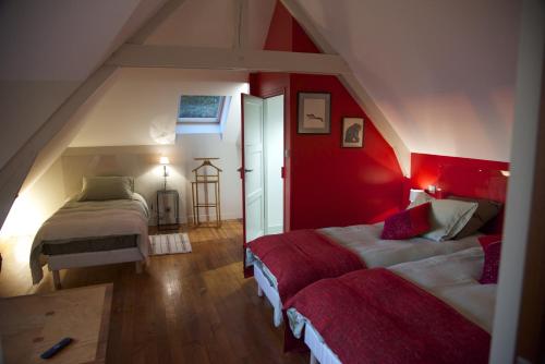Schlafzimmer im Dachgeschoss mit 2 Betten und einer roten Wand in der Unterkunft La Bellevue, maison entière in Hénouville