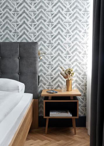 a bedroom with a bed and a nightstand with a table at Hotel MIO by AMANO in Munich