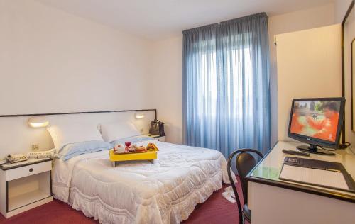 a hotel room with a bed, desk and television at Hotel Quadrifoglio in Cagliari