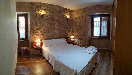 a bedroom with a large bed and two windows at Casa Rural La Veterinaria in Aldeadávila de la Ribera