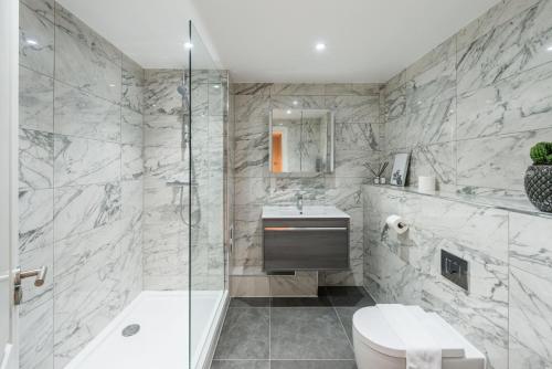 a bathroom with a shower and a toilet and a sink at The Carlyle - Stunning Serviced Apartments in London
