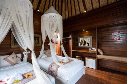 a bedroom with two beds with mosquito nets at Breeze Villa in Nusa Lembongan