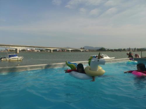 a child in a swimming pool with a dragon float at Riverbank Dungun Guesthouse & Cafe in Dungun