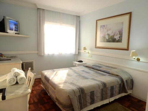 um quarto de hotel com uma cama e uma janela em Hotel Bruggemann em Florianópolis