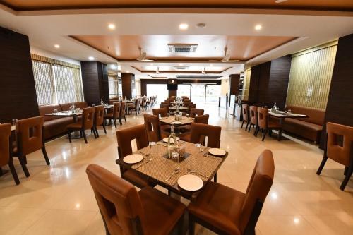 un ristorante con tavoli e sedie in una stanza di RNS ONE a Subrahmanya