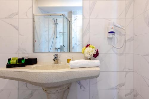 a bathroom with a sink and a mirror at Marina Burgas Hotel in Burgas