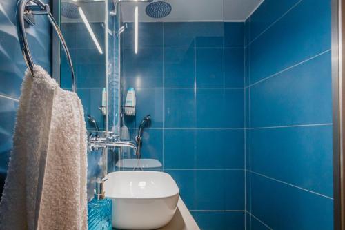 a blue tiled bathroom with a toilet and a shower at San Marco Luxury Apartment Zante in Zakynthos Town