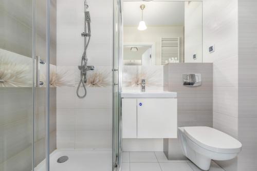 a white bathroom with a toilet and a shower at Apartamenty Osiedle Bursztynowe by Renters in Kołobrzeg