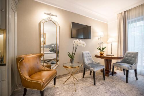 a living room with a table and chairs and a mirror at Bachleda Luxury Hotel Kraków - MGallery Collection in Kraków