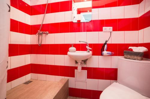 baño rojo y blanco con aseo y lavamanos en Невелика Smart квартира в центрі для пари en Leópolis