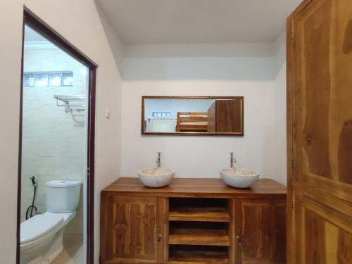 a bathroom with two sinks and a toilet and a mirror at Gedhong Hostel in Nusa Penida