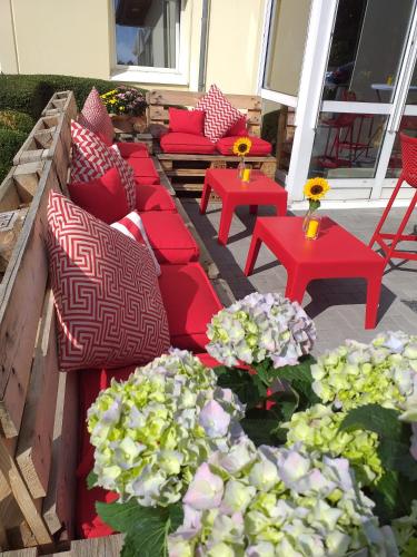 a patio with red couches and tables and flowers at ibis Köln Frechen in Cologne