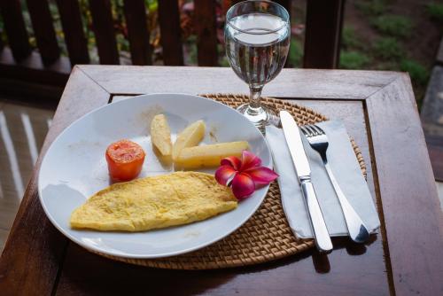 een bord eten op tafel met een glas wijn bij Gedhong Hostel in Nusa Penida