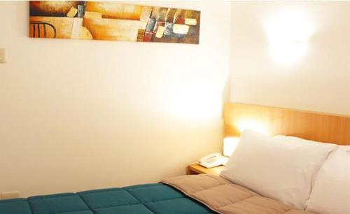 a bedroom with a bed and a phone on a table at Hotel Romano in Concepción