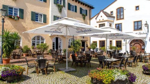 an outdoor patio with tables and chairs and umbrellas at Wailtl Hotel in Dorfen