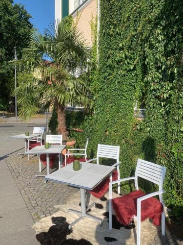 a group of tables and chairs next to a wall at Bahnhofshotel Die Neue Bühne in Bad Saarow
