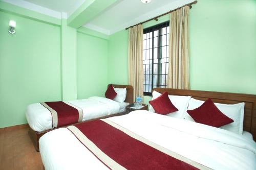 2 camas en una habitación con paredes verdes y ventana en Allied Hotel, en Bālāju