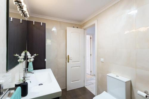 een badkamer met een wastafel, een toilet en een spiegel bij Spacious Beachfront Flat with Sea Views and Private Indoor Parking in Benalmádena