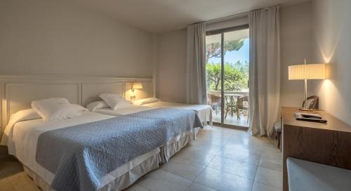 Habitación de hotel con 2 camas y ventana grande. en S'Agaró Hotel Spa & Wellness, en S'Agaró