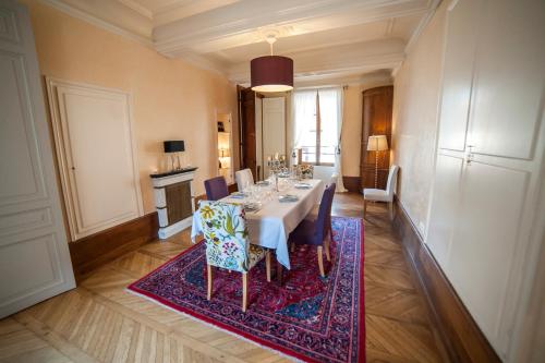 a dining room with a table and chairs on a rug at Maison des 7 lieux in Chablis