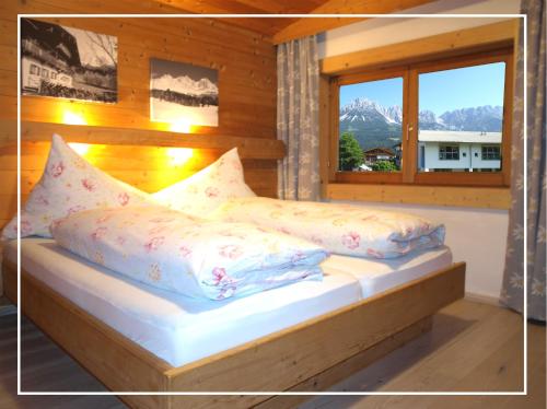 a bedroom with a bed with pillows and a window at Alpen Chalet ELLMAU Zentrum in Ellmau