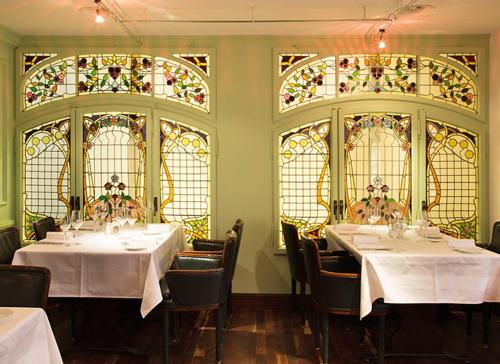 a dining room with two tables and stained glass windows at Hotel Taverne zum Kreuz in Olten