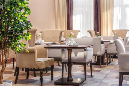 um restaurante com mesas, cadeiras e plantas em Hotel Minin on Pozharskogo Street em Níjni Novgorod